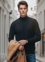 A man in a 98degreenorth Men’s Black Merino Wool Turtle Neck Sweater holds a tan coat on a city street.