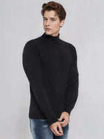 A man models the 98degreenorth Men's Black Merino Wool Turtle Neck Sweater, exuding classic winter elegance.