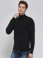 A man in a 98degreenorth Men’s Black Merino Wool Turtle Neck Sweater poses against a light gray background.