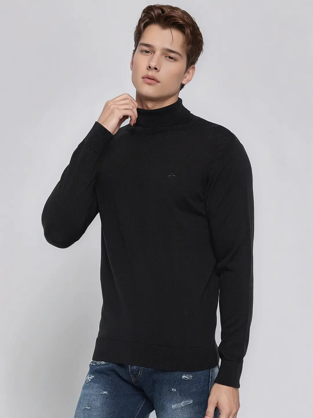 A man in a 98degreenorth Men’s Black Merino Wool Turtle Neck Sweater poses against a light gray background.