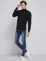Man in a 98degreenorth Black Merino Wool Turtle Neck Sweater, blue ripped jeans, and white sneakers on gray background.