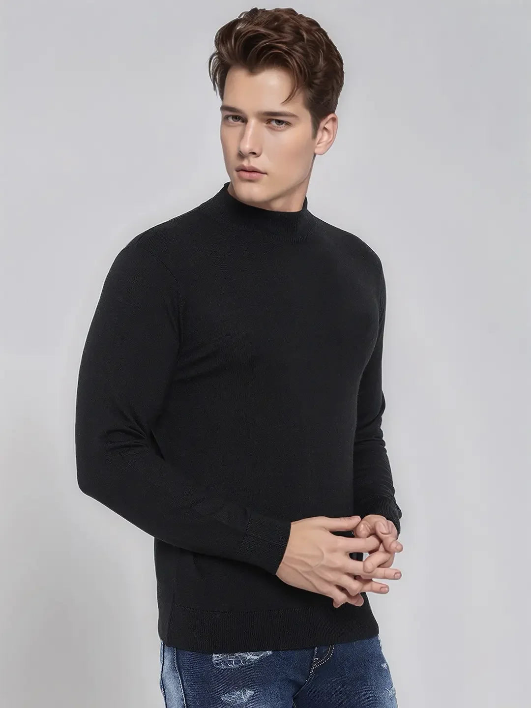 Man wears 98degreenorth Men's Black Merino Wool Turtle Neck Sweater, posing in blue jeans against a light gray background.