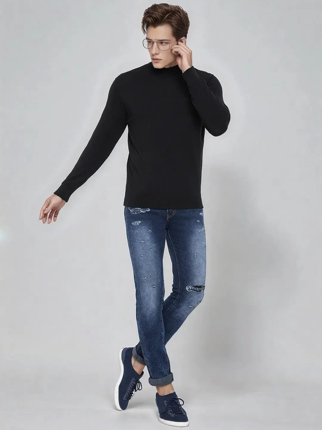 A man in glasses wears a 98degreenorth Men’s Black Merino Wool Turtle Neck Sweater against a light gray background.