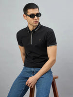 Man in 98degreenorth Handmade Black Polo T-Shirt with contrast tipping, blue jeans, and sunglasses on a stool.