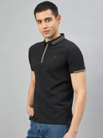 Man in 98degreenorth Men's Black Polo T-Shirt—Handmade Series with Contrast Tipping, hand in pocket on grey backdrop.