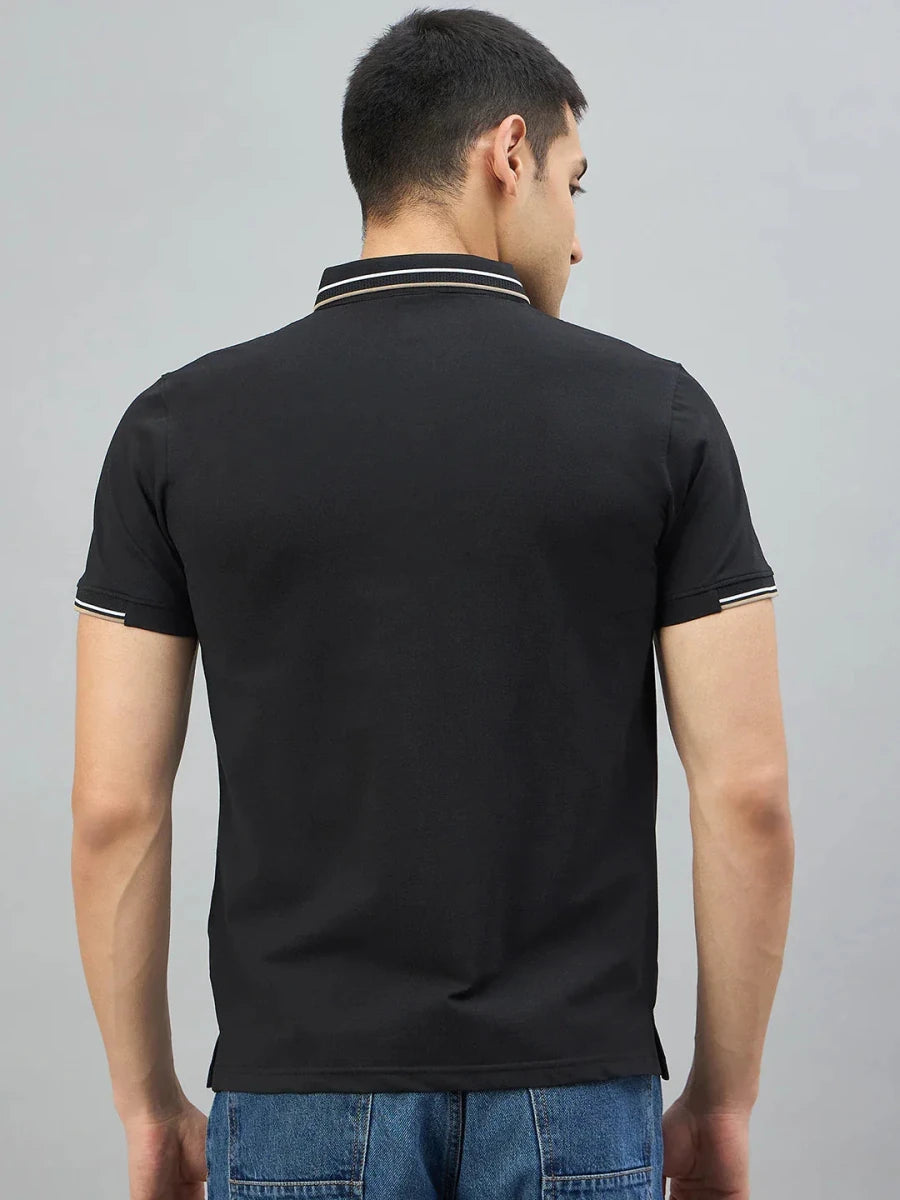 A man in a Men's Black Polo T-Shirt by 98degreenorth is seen from behind, wearing blue jeans against a gray background.