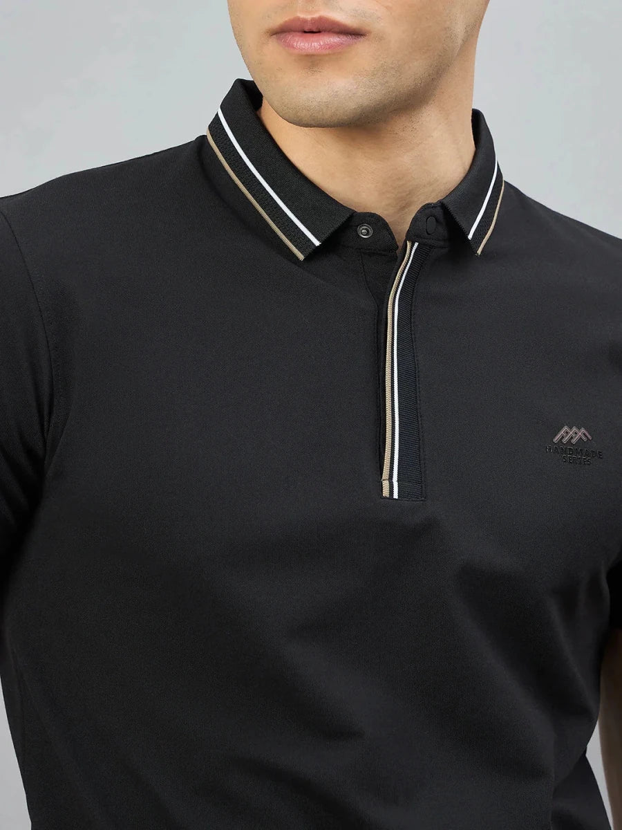 Man wearing 98degreenorth Handmade Series black polo with contrast tipping and embroidered chest logo.