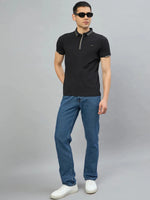 Man wears 98degreenorth Men's Black Polo T-Shirt — Handmade Series, standing against a plain gray background.