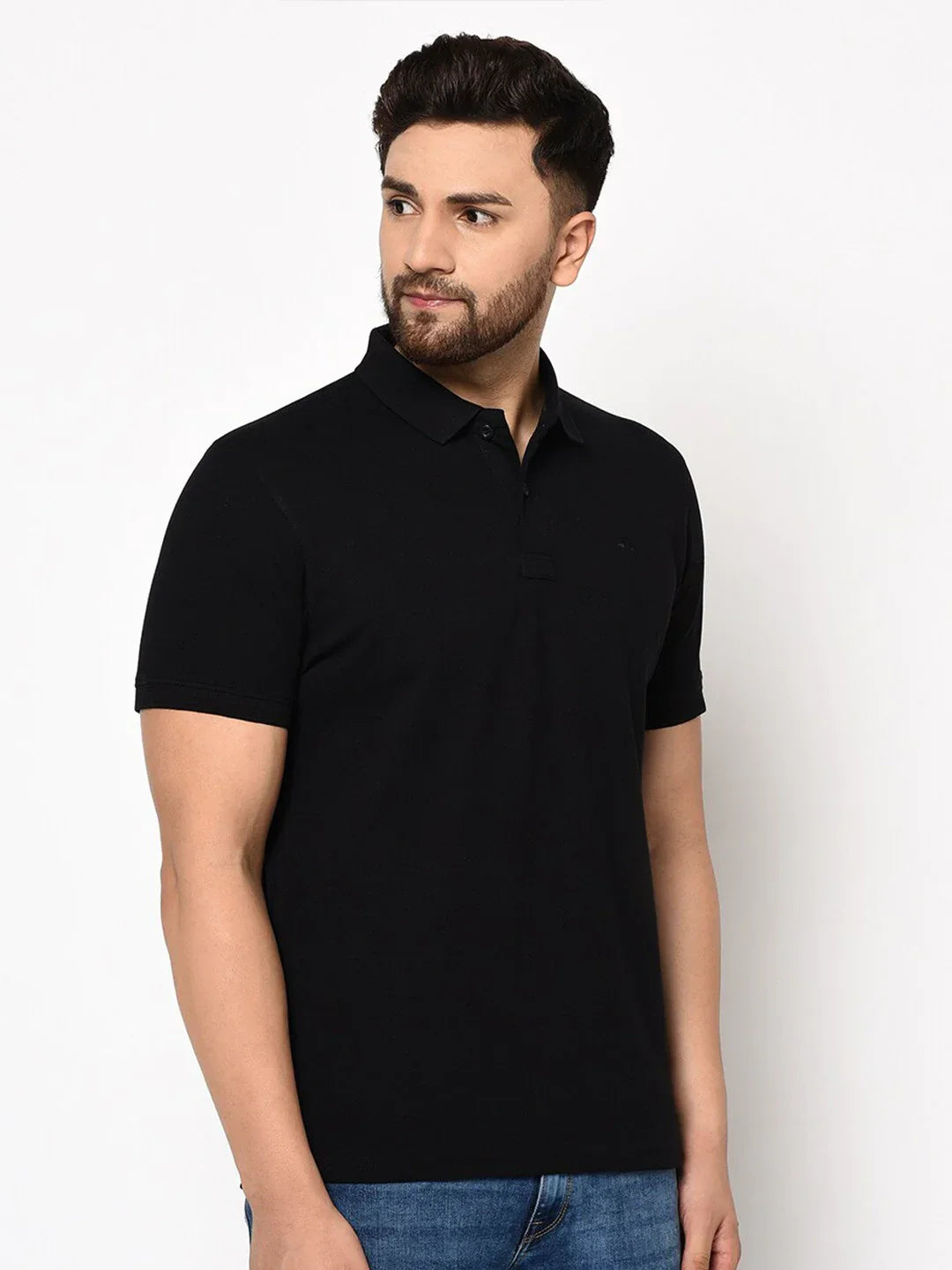 Man wears 98degreenorth Men's Black Polo T-Shirt—Stretch Cotton Pique Knit, styled with blue jeans, against white background.