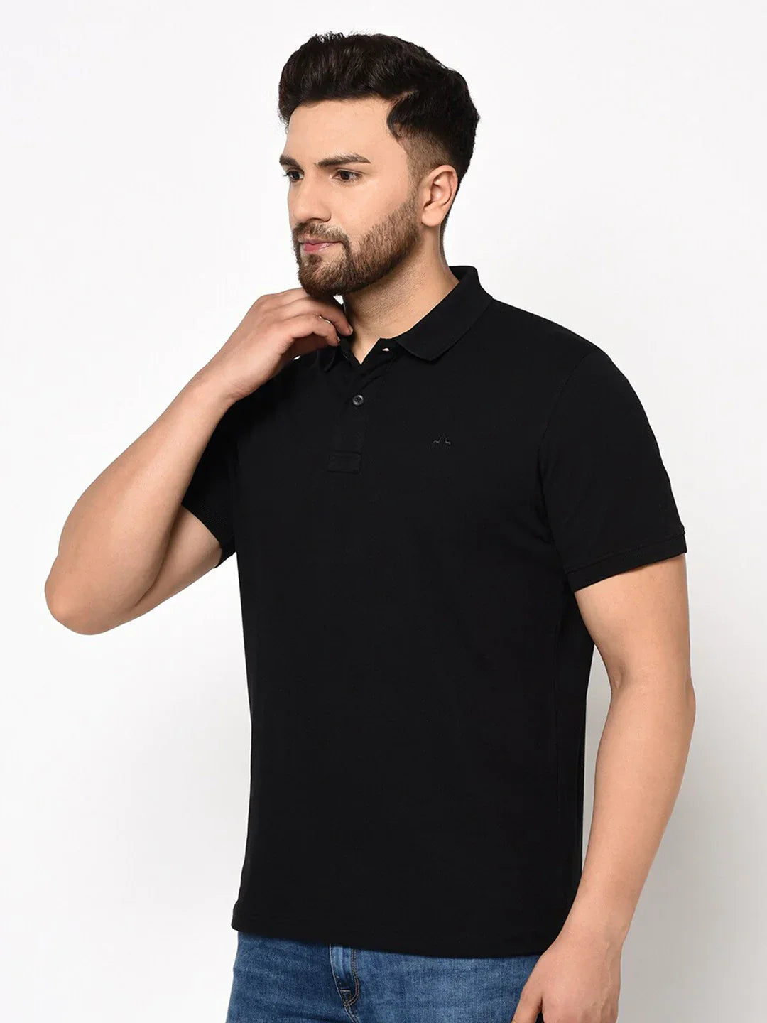 Man wears 98degreenorth Men's Black Polo T-Shirt—Stretch Cotton Pique Knit, paired with blue jeans, against a white background.