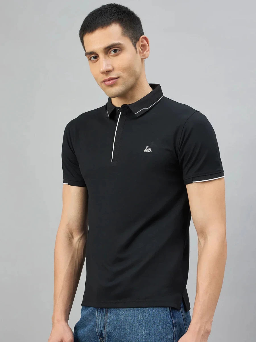 A man wears the 98degreenorth Men's Black Polo T-Shirt with White Tipping, standing against a light gray background.