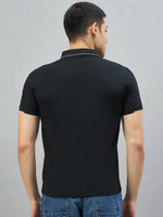 A man wears a 98degreenorth Men's Black Polo T-Shirt with White Tipping (LA Logo), shown from the back on gray.