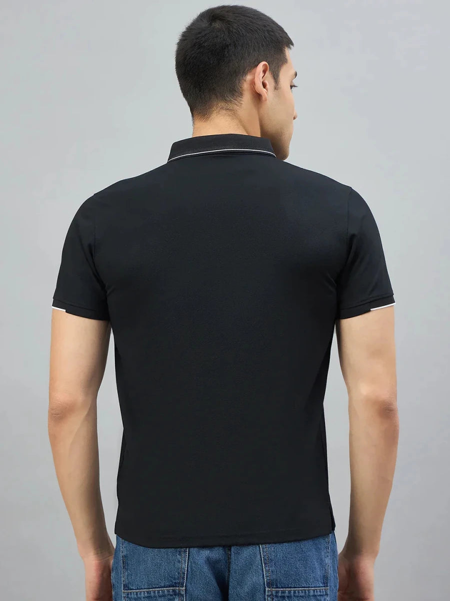A man wears a 98degreenorth Men's Black Polo T-Shirt with White Tipping (LA Logo), shown from the back on gray.
