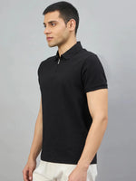 Man wearing 98degreenorth Men's Black Quarter Zip Polo T-Shirt — Popcorn Knit, paired with white pants on a gray background.