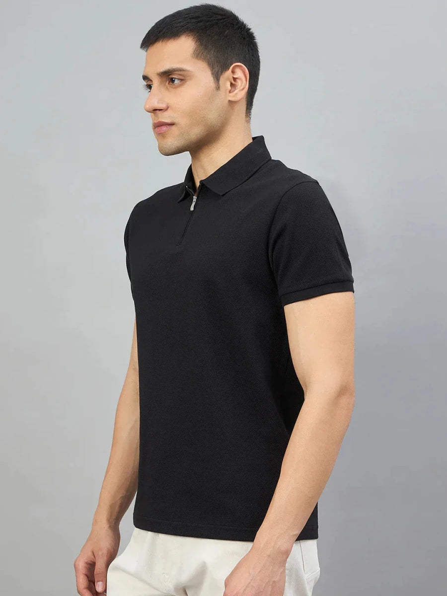 Man wearing 98degreenorth Men's Black Quarter Zip Polo T-Shirt — Popcorn Knit, paired with white pants on a gray background.