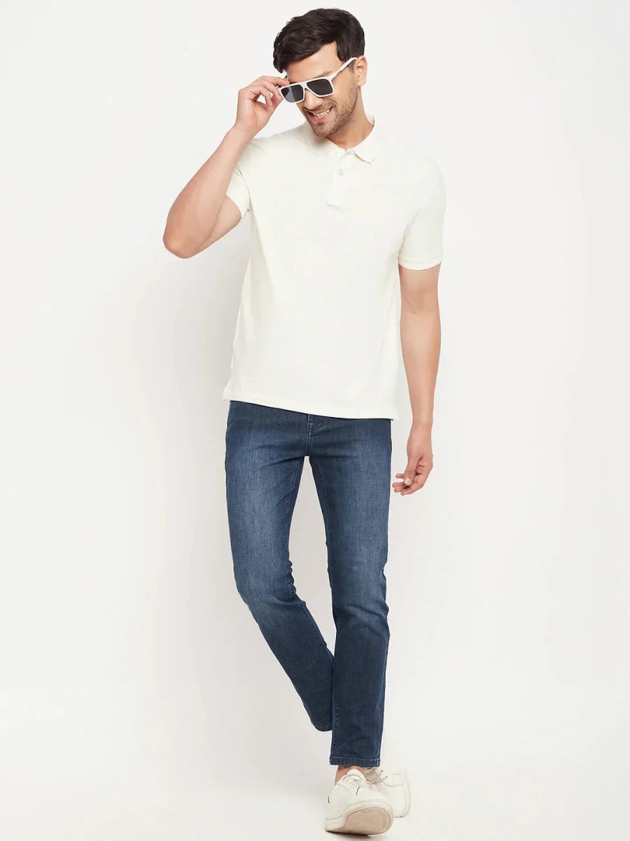 Man in a 98degreenorth butter yellow striped polo, blue jeans, white sneakers & sunglasses against a white background.