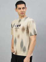 Man wearing a Men's Camel Abstract Ikat Print T-Shirt by 98degreenorth, standing against a plain gray background.