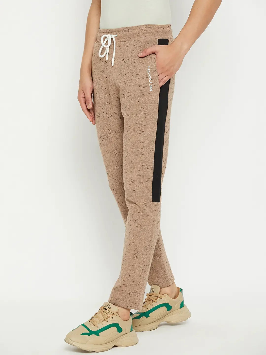 Man in 98degreenorth Men’s Camel Fleece Trackpants with contrast side stripe, beige sneakers, hand in pocket.