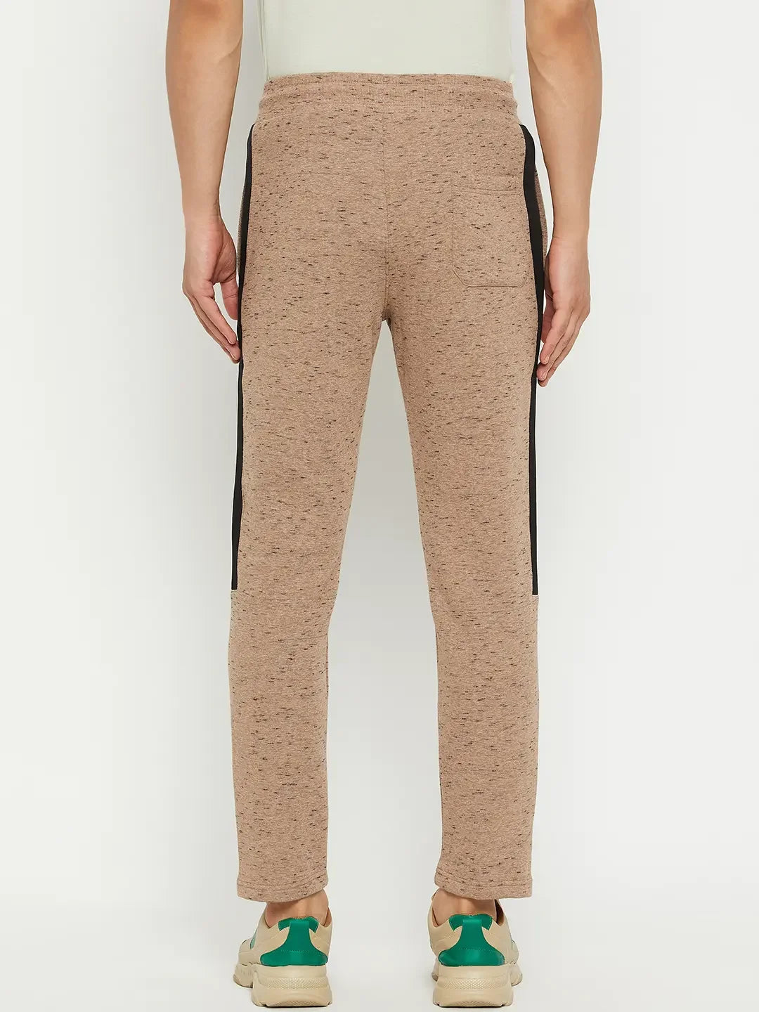 A person wears 98degreenorth Men’s Camel Fleece Trackpants with a black side stripe and sneakers, viewed from the back.