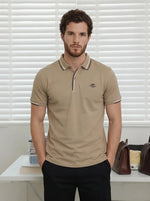 Man with brown hair and beard wears a Men’s Camel Polo T-Shirt by 98degreenorth, standing in a bright room with blinds.
