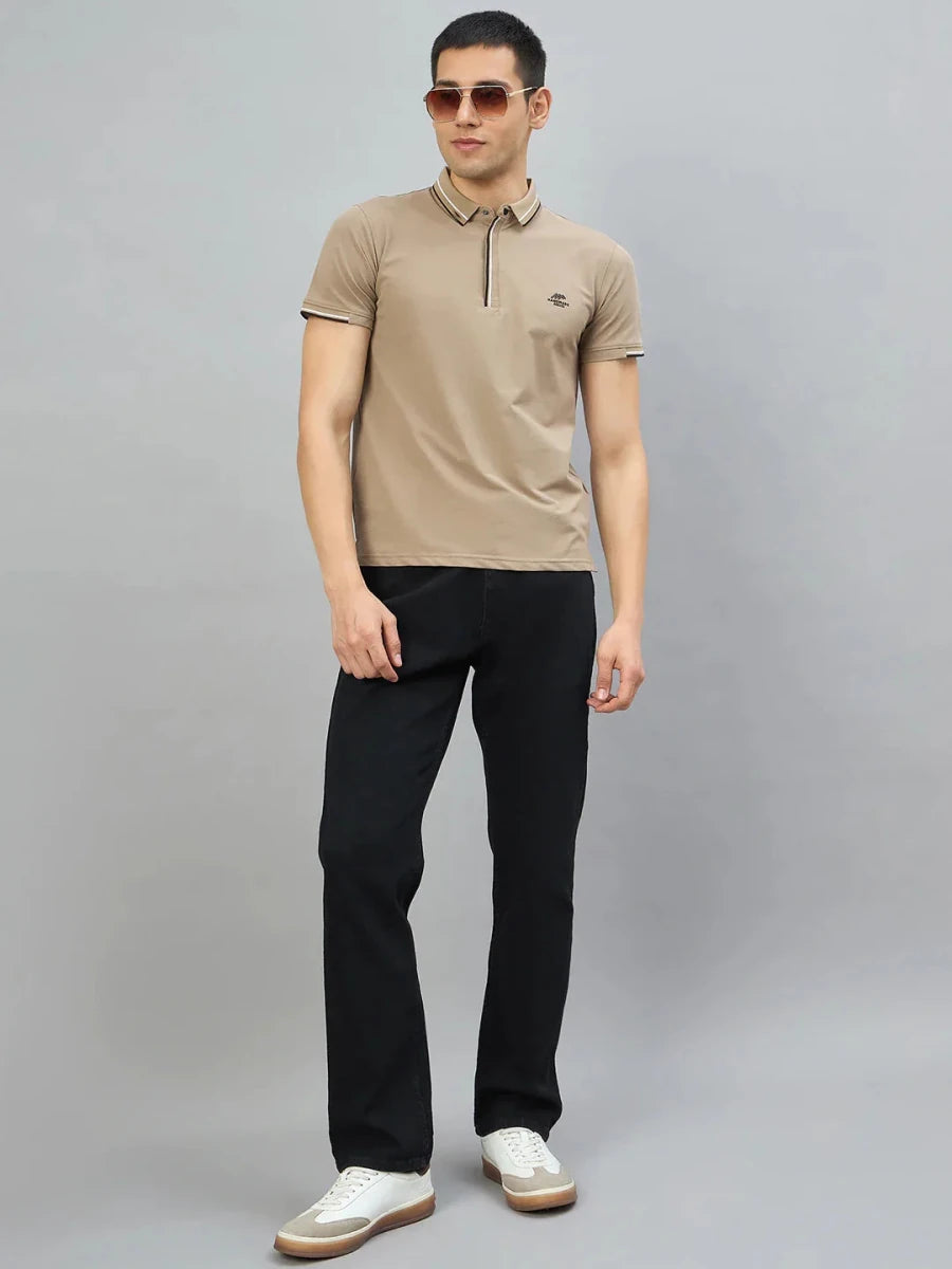 Man in 98degreenorth Men's Camel Polo T-Shirt, black pants, sunglasses, and white sneakers against a gray background.