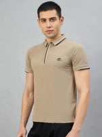 Man wears 98degreenorth Men's Camel Polo—Handmade Series with contrast collar tipping, on a gray background.