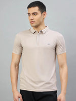 Man wears 98degreenorth Men's Camel Polo T-Shirt with White Tipping, LA Logo, against a plain gray background.