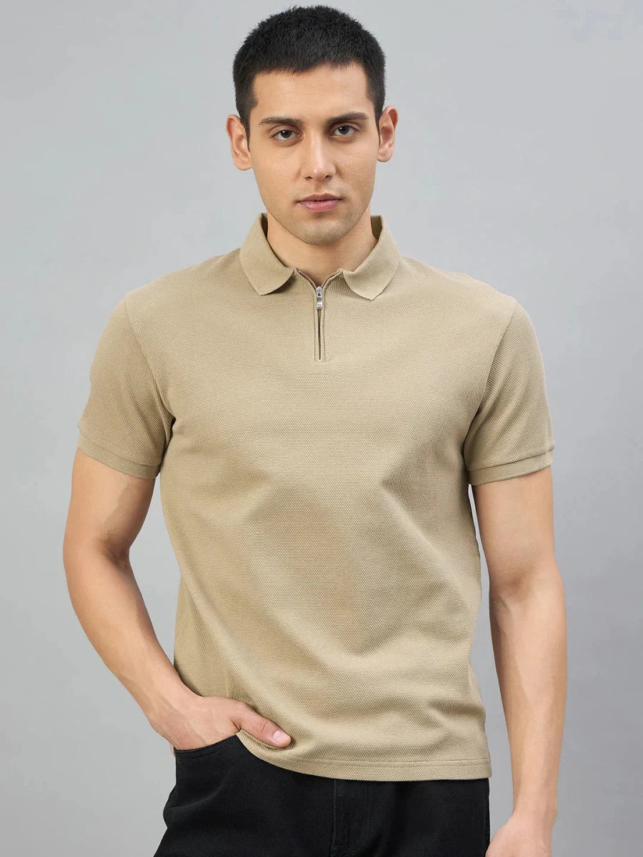 A man wears the 98degreenorth Men's Camel Quarter Zip Polo T-Shirt—Popcorn Knit, with black pants, on a gray background.