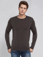 A man wears the 98degreenorth Men’s Charcoal Merino Wool Sweater, pairing it with blue jeans against a gray background.