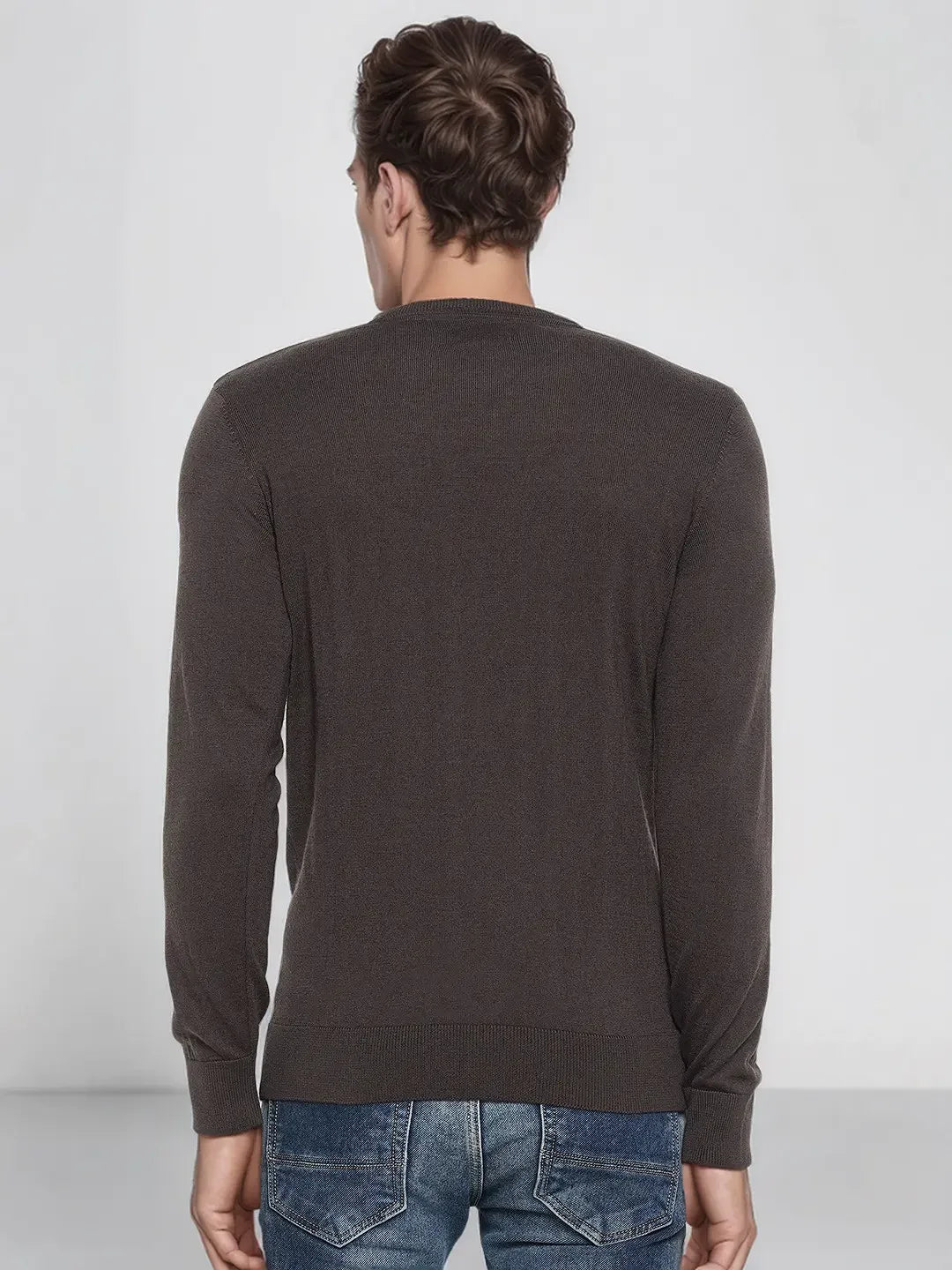 A man in a 98degreenorth Charcoal Merino Wool Sweater, seen from behind, with blue jeans on a light gray background.