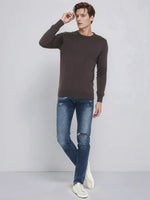 Man in a 98degreenorth Men’s Charcoal Merino Wool Round Neck Sweater, blue jeans, and sneakers on a light gray background.