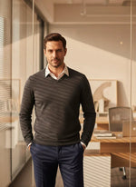 A man in business attire wears the 98degreenorth Men’s Charcoal Merino Wool V-Neck Sweater in a modern office.