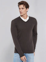 Man wears 98degreenorth Men’s Charcoal Merino Wool V-Neck Sweater over a white shirt and jeans, against a plain backdrop.