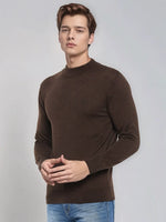 A man wears the 98degreenorth Coffee Merino Wool Turtle Neck Sweater with blue jeans against a light gray background.