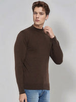A man models the 98degreenorth Men’s Coffee Merino Wool Turtle Neck Sweater with blue jeans on a light gray background.