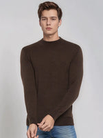 A man wears the 98degreenorth Coffee Merino Wool Turtle Neck Sweater, styled with blue jeans against a plain background.