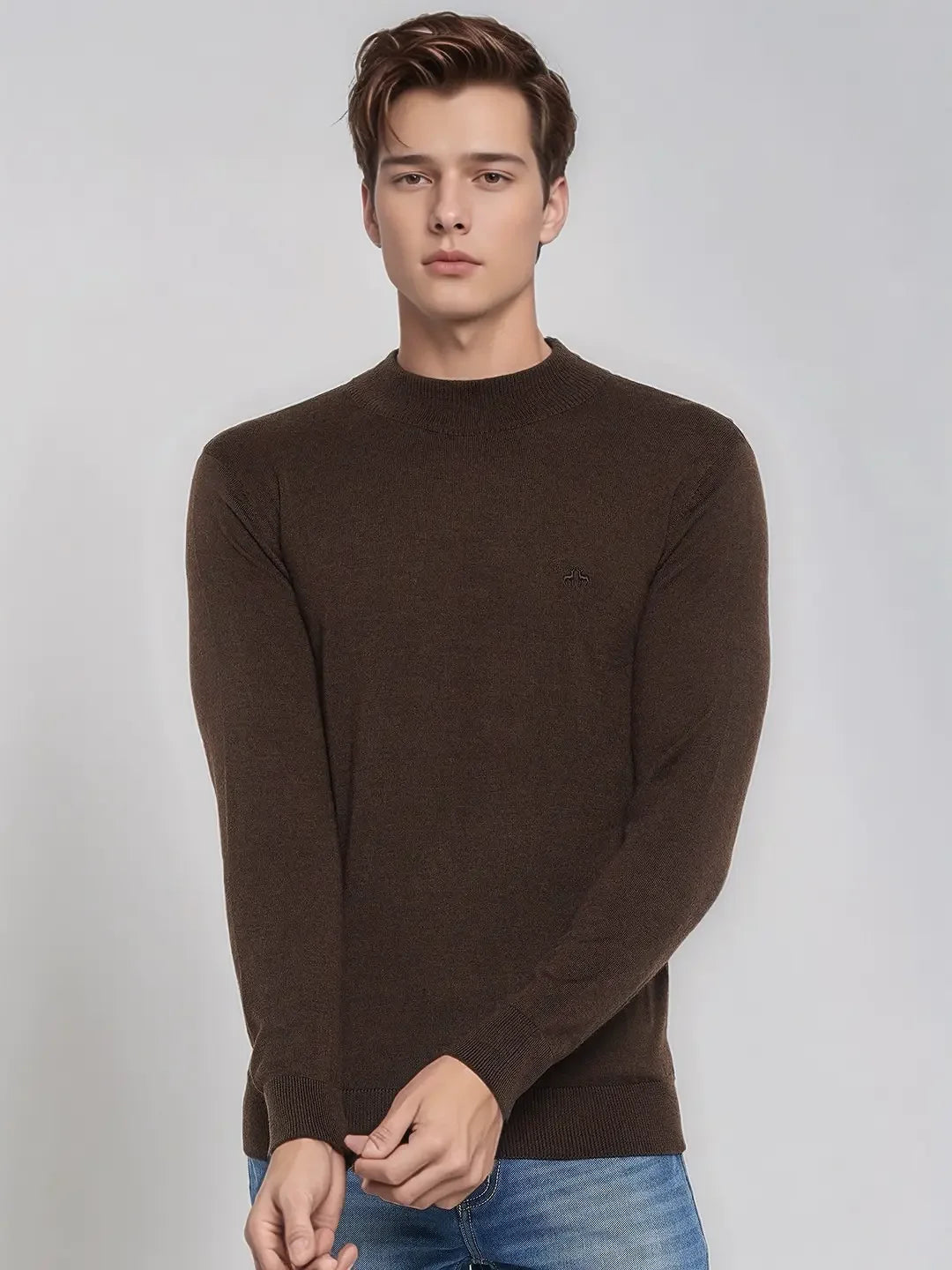 A man wears the 98degreenorth Coffee Merino Wool Turtle Neck Sweater, styled with blue jeans against a plain background.