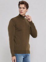 A man in a 98degreenorth Men’s Coffee Merino Wool Turtle Neck Sweater and blue jeans poses against a light gray background.