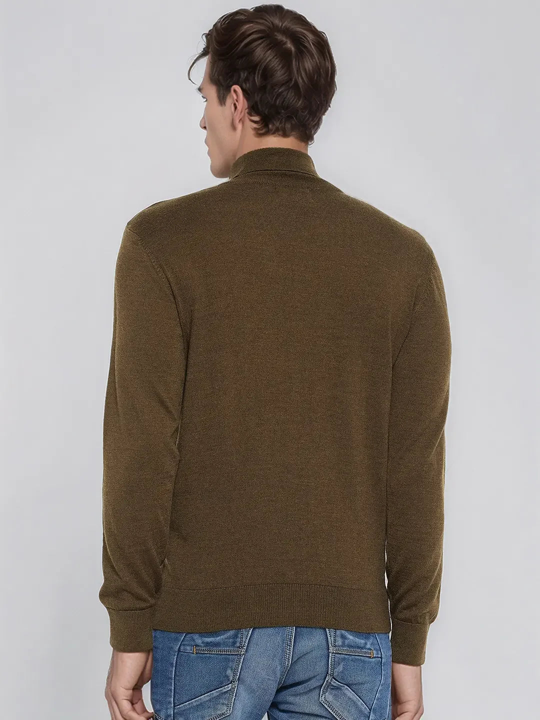 A man in a 98degreenorth Men’s Coffee Merino Wool Turtle Neck Sweater and blue jeans stands with his back to the camera.