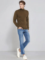 Man in 98degreenorth Men’s Coffee Merino Wool Turtle Neck Sweater, blue jeans, and white sneakers on gray backdrop.