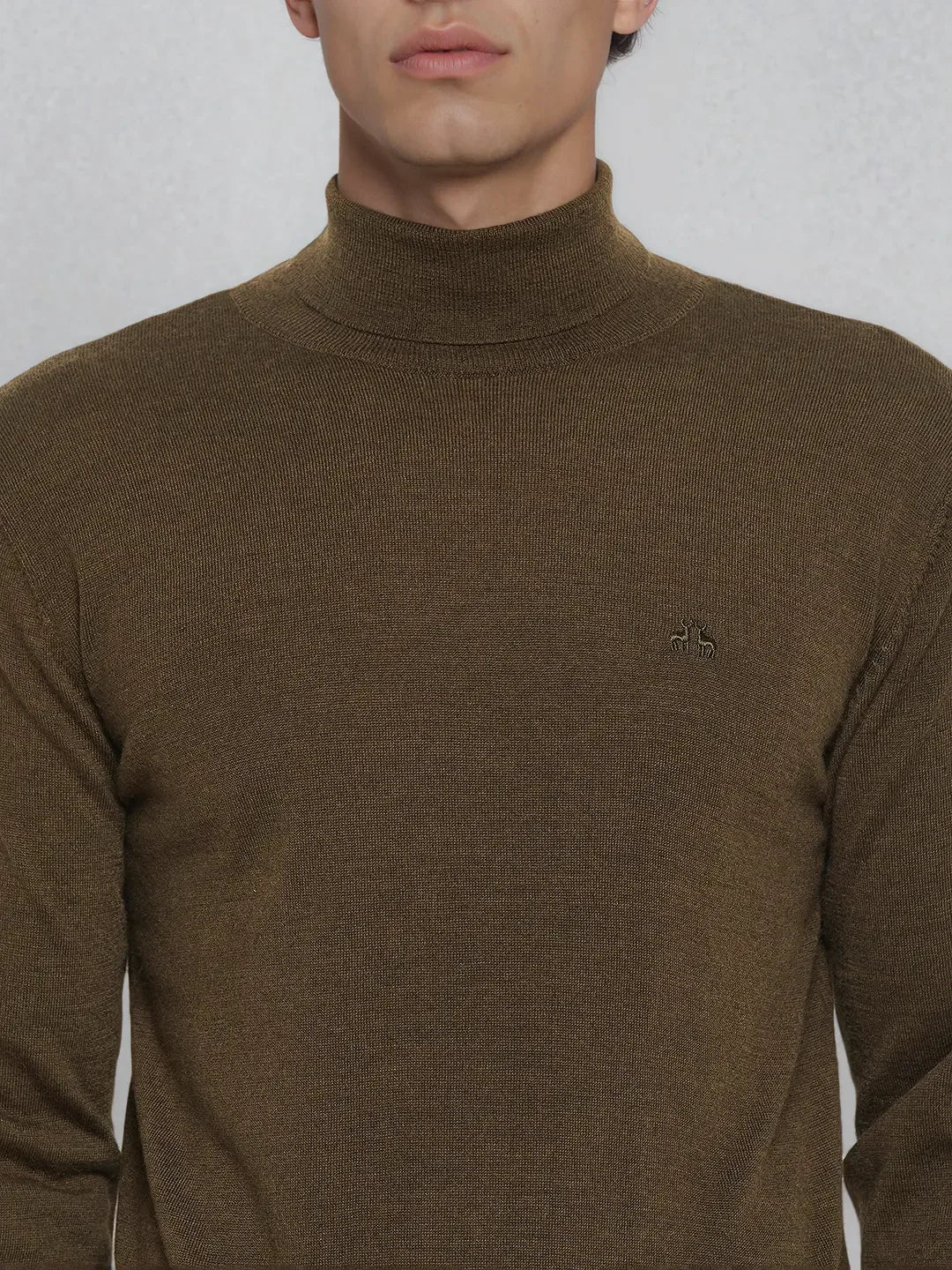 Man in 98degreenorth Coffee Merino Wool Turtle Neck Sweater, shown from shoulders up with small logo.