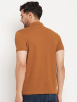 Man in 98degreenorth Men's Copper Polo T-Shirt—Pure Cotton Pique with chest pocket, paired with dark jeans.