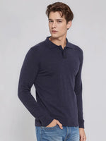 A man wears the 98degreenorth Men’s Dark Denim Merino Wool Polo Neck Sweater, a soft knit pullover for smart casuals.