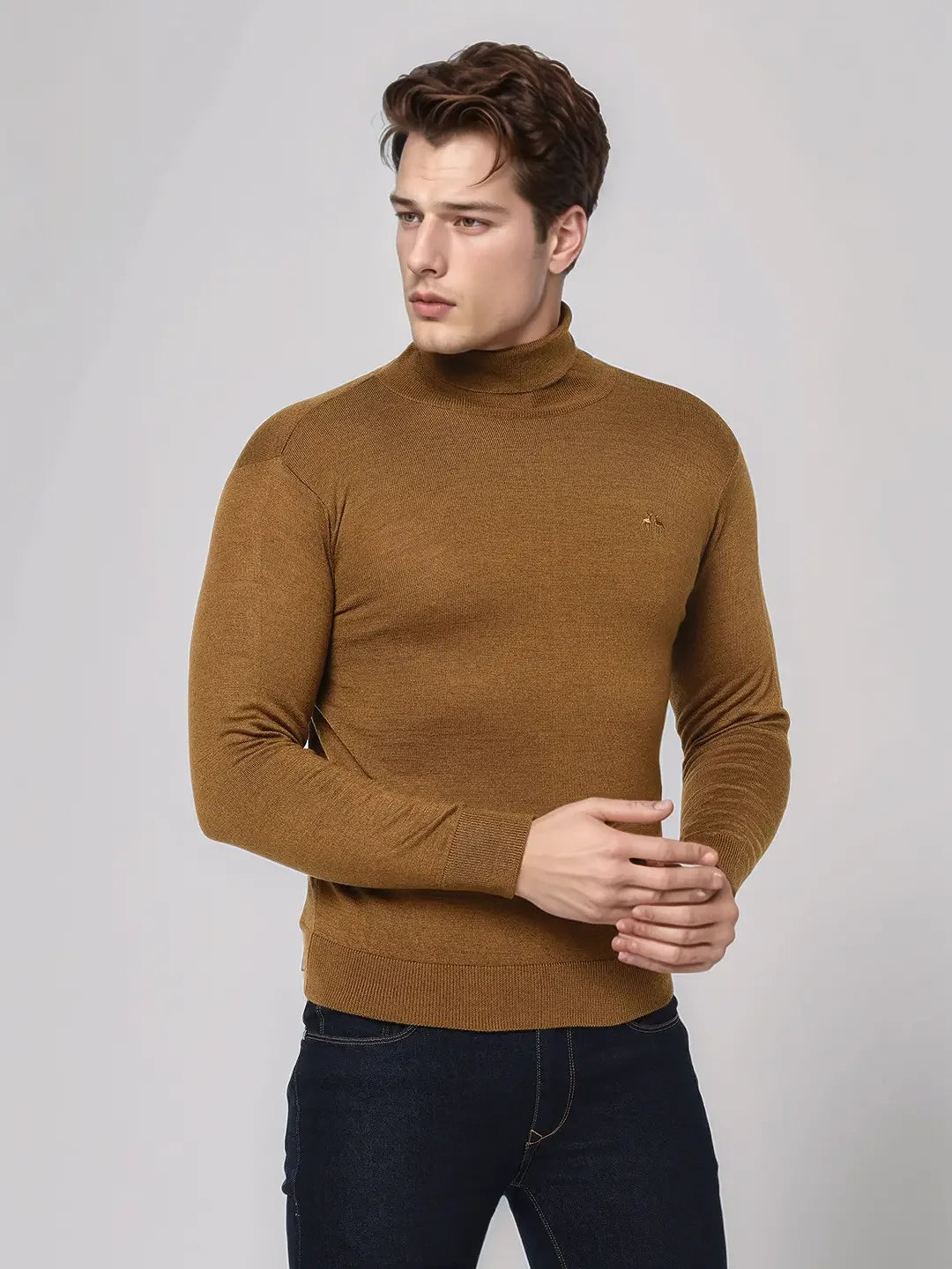 A man in a 98degreenorth dark khaki merino wool turtleneck sweater stands against a plain light gray background.