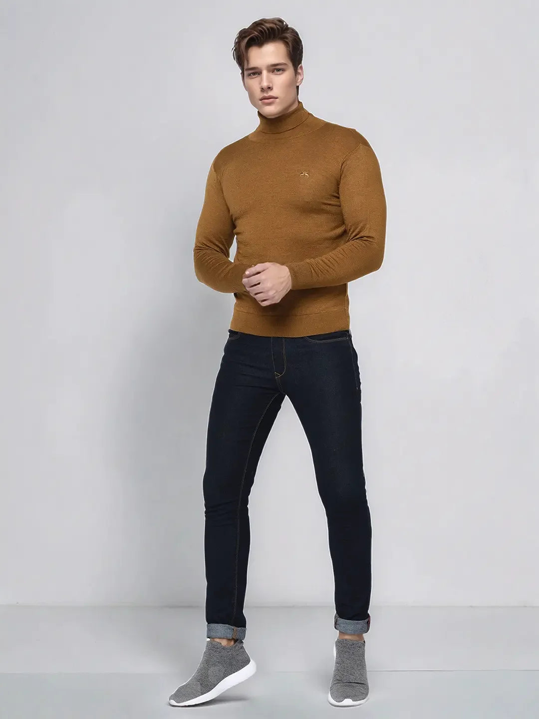 A man in a 98degreenorth dark khaki merino wool turtle neck sweater stands against a plain light background.