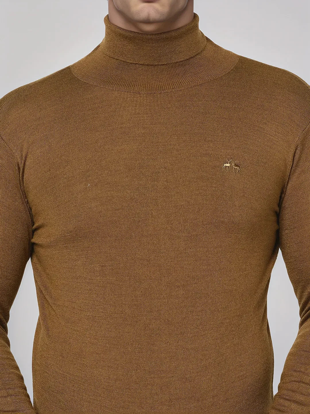 A person in a 98degreenorth Men’s Dark Khaki Merino Wool Turtle Neck Sweater with an embroidered chest logo.