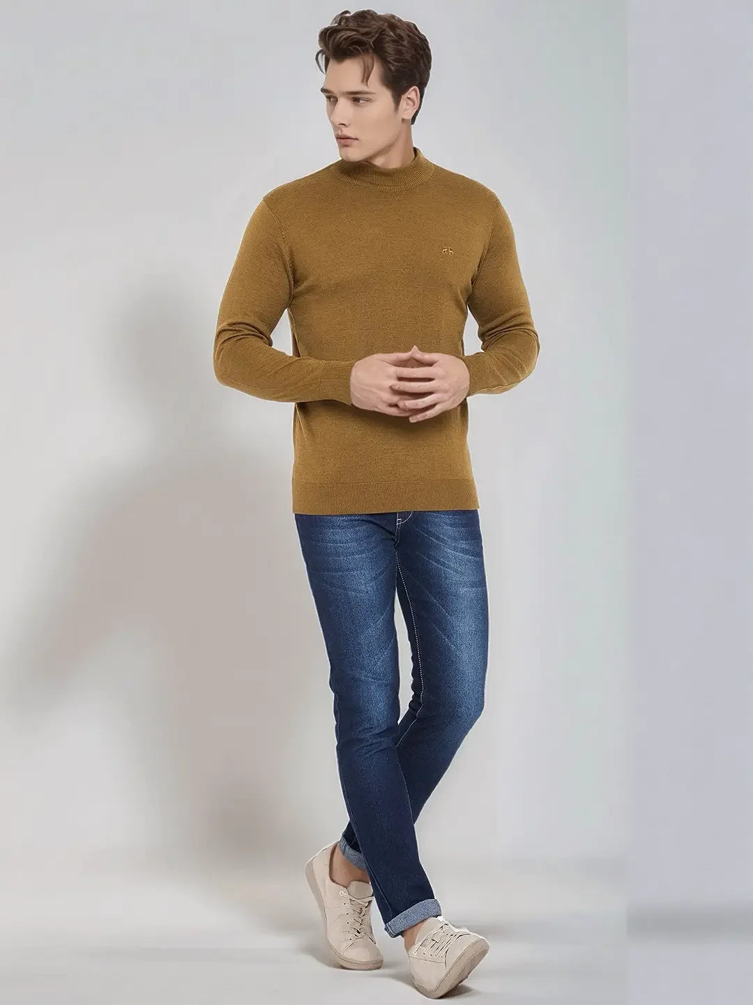 Man wearing 98degreenorth Men’s Dark Khaki Merino Wool Turtle Neck Sweater, blue jeans, and beige sneakers.
