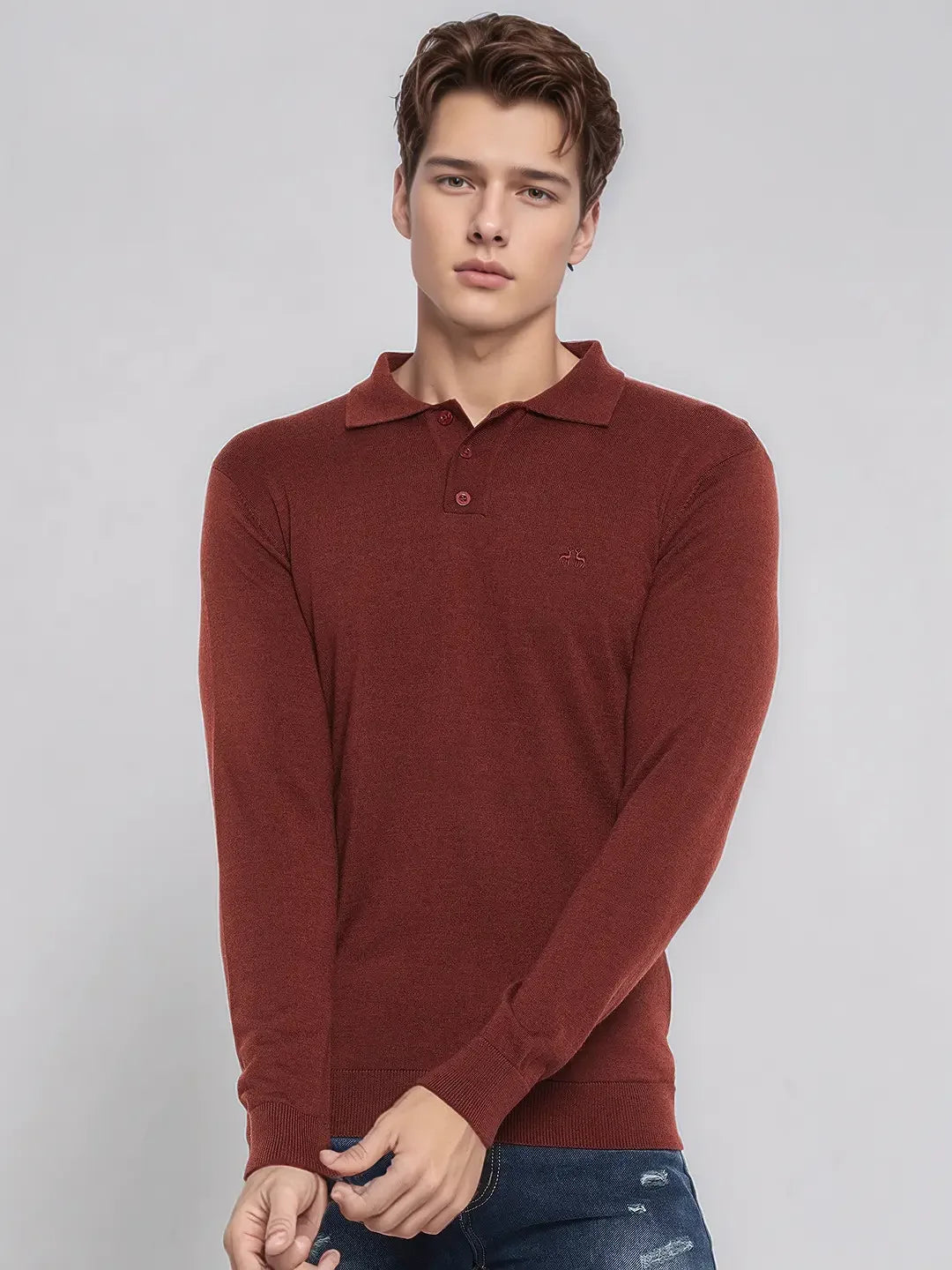 A man wears a 98degreenorth Men’s Dark Maroon Merino Wool Polo Neck Sweater with blue jeans against a plain backdrop.