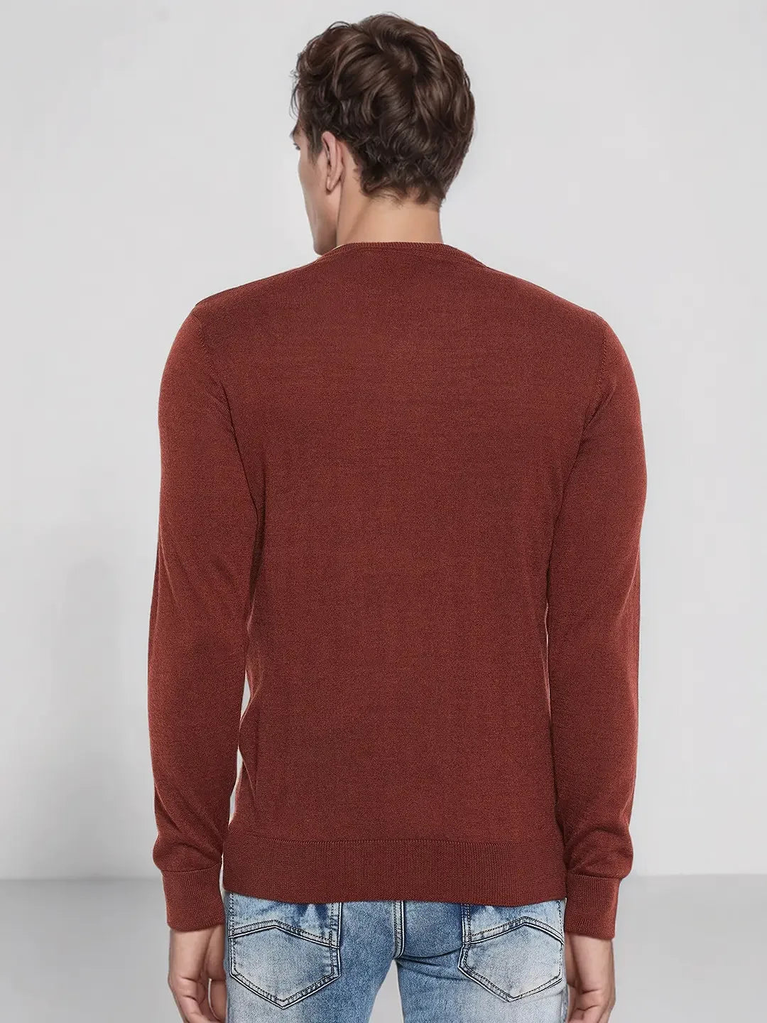 Man wears 98degreenorth Men’s Dark Maroon Merino Wool V-Neck Sweater and light blue jeans, facing away.