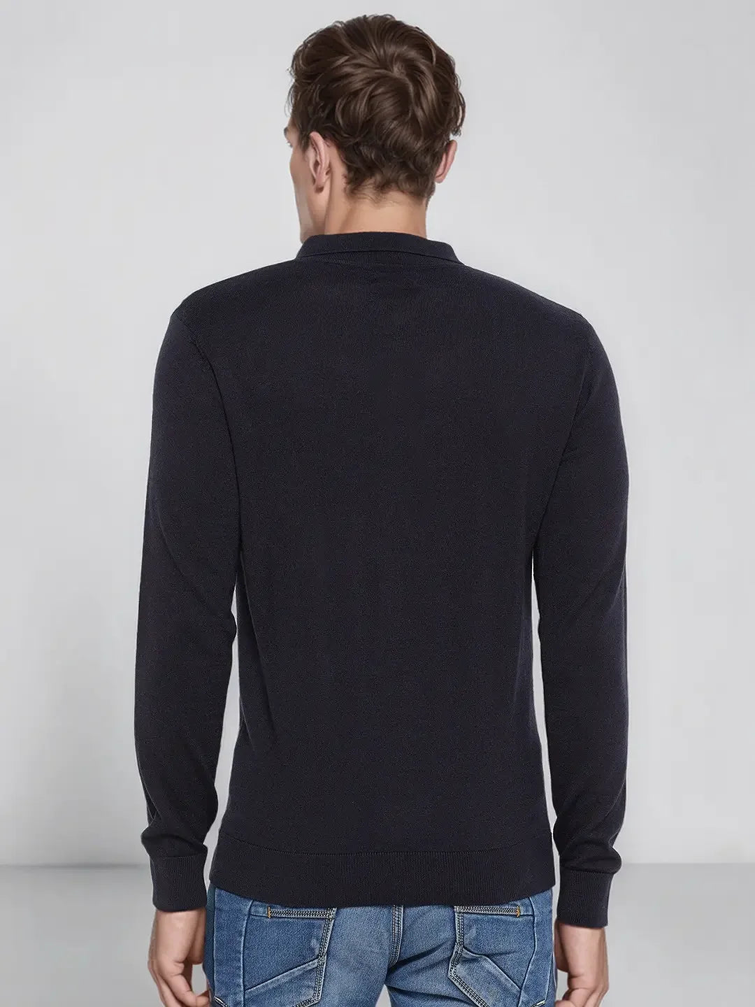 A man wears a 98degreenorth Men’s Dark Navy Merino Wool Polo Sweater, standing with his back to the camera.